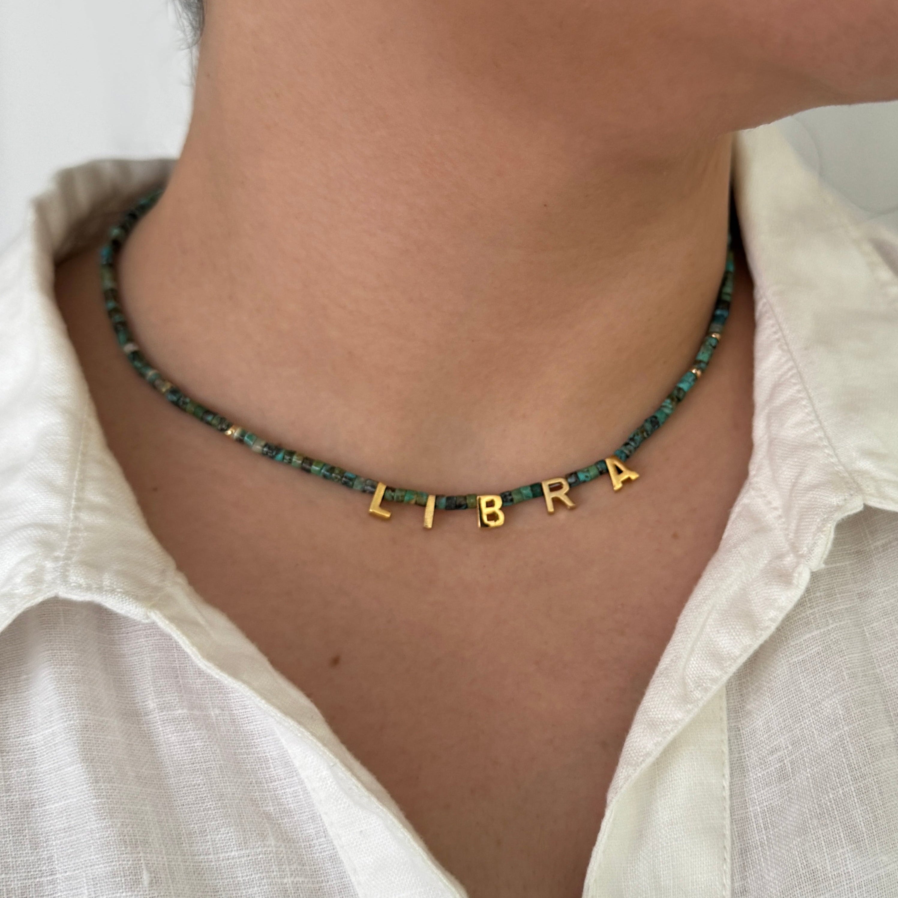 Necklace with 'LIBRA' pendant worn by a person in a white shirt